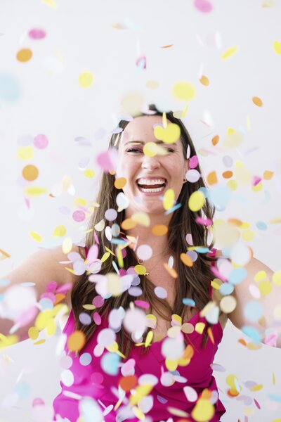 Woman tossing bright colorful confetti into the air during her NYC brand photoshoot