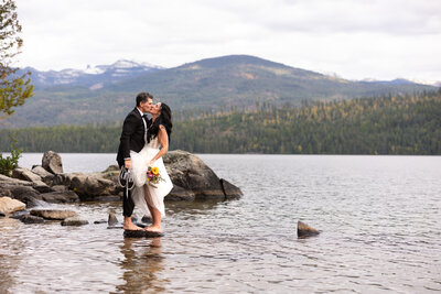 Bride and Groom standing face to face barefoot on a rock on Priest Lake