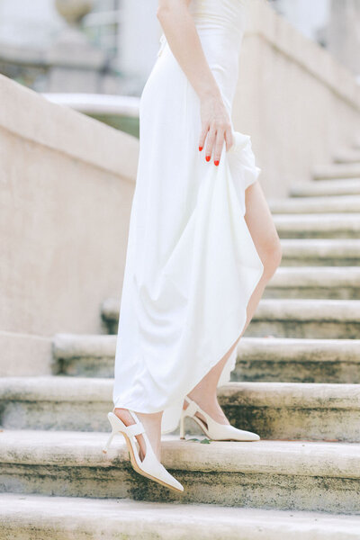 Bride in white dress with white shoes walks up stone stairs at Atlanta History Center Swan House