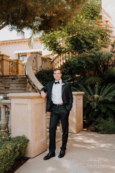 groom standing next to stone stairs outside
