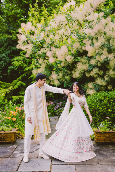 Indian groom twirling the bride in a white lehnga before their hindu wedding ceremony at the buttermilk falls inn in milton ny