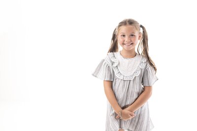 Smiling girl in gray striped dress on white background