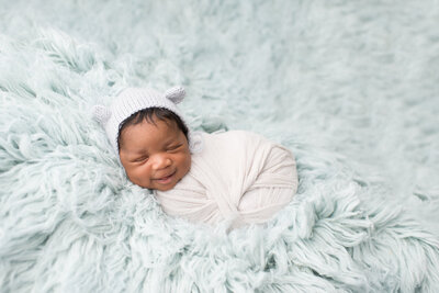 baby wrapped in white blanket  with baby blue backdrop