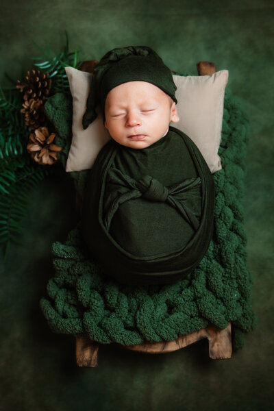 Happy new parents cradle their newborn daughter between them while standing in a window captured by a Milwaukee Newborn Photographer