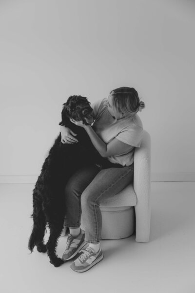 Natural light brand portrait of Emily Rowan, Michigan and Ohio photographer, with her dog in a cozy studio session.