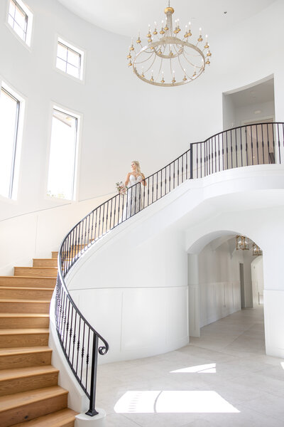 wedding photographer in Texas poses bride at top of winding staircase at The Preserve in Canyon Lake