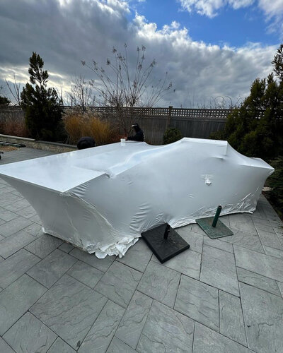 Boat covered in shrink wrap, placed on patio tiles