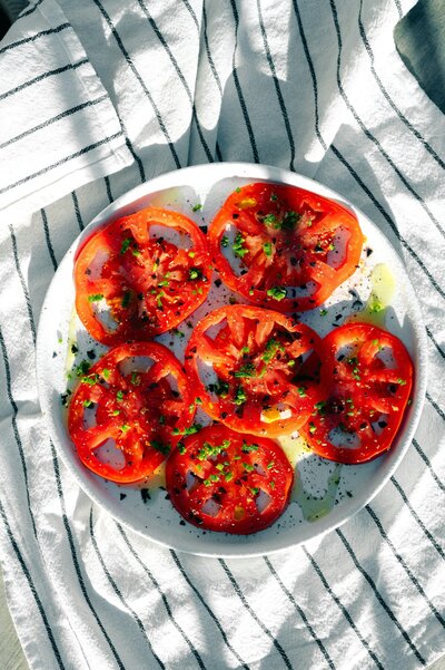 Sliced tomatoes on a plate sitting on striped fabric