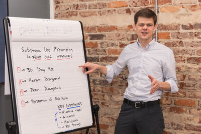 Man in business casual outfit pointing to a tripod paper board during a meeting in Atlanta GA