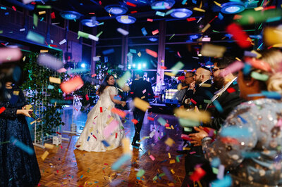 A couple exits their wedding reception amid colorful confetti