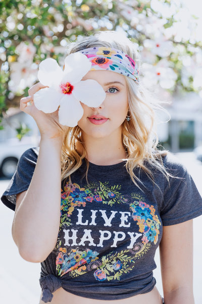  dynamic portrait of a teen girl with an oversized flower and a live happy T-shirt for a senior portrait session in Santa Barbara, California