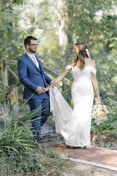 bride and groom walking through a garden while holding hands