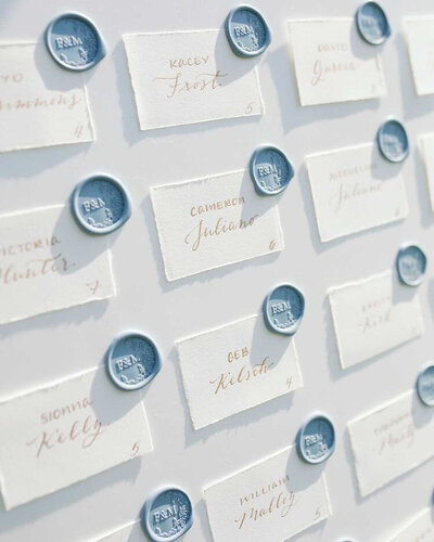 White handmade paper name cards with gold calligraphy and dusty blue wax seals