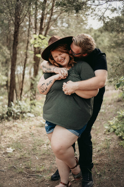 couple laughing and embracing in the woods