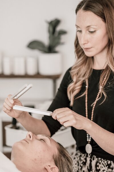 Woman using facial tuning forks and reiki in a holistic facial