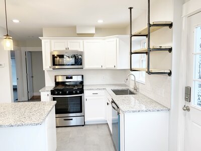 newly renovated white kitchen featuring  industrial open shelving