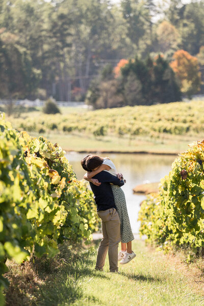 A couple embraces in a vineyard just seconds after getting engaged.