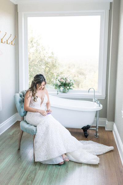 A bride sits next to the clawfoot tub in the Kendall Point bridal suite.