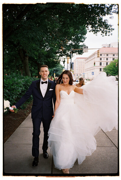 Groom in a tux, bride in a wedding gown running down Oakland, Pittsburgh PA street