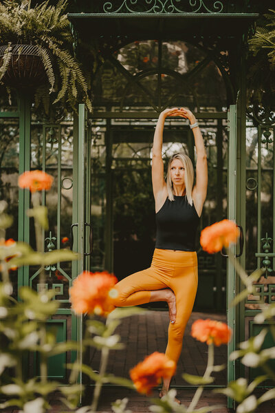 Life Coach Branding Session at the Denver Botanical Gardens doing a yoga pose at the Woodland Mosaic and flowers in the foregorund