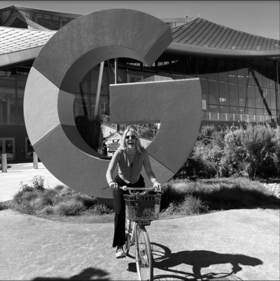 Woman on a bike in front of large Google sign