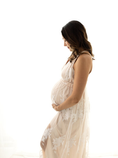 pregnant mother holding belly wearing pink maternity gown for studio maternity photoshoot Cleveland Family photographer