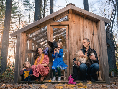 Family with dogs posing outside a wooden shed, photographed by Boston family photographer Corey Flint.