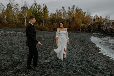 Two Grooms Laughing and Sharing Their Wedding Cake during their Lake Superior Elopement