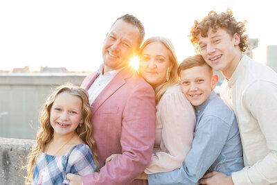 family of 5 smiling at camera wearing sundays best clothing