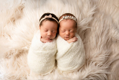 Newborn twins posed on white fur during their baby photos session in Minnesota.