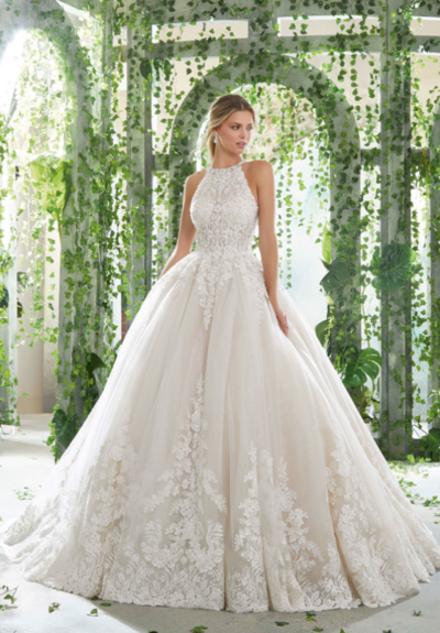 The Surim wedding dress features beaded alençon lace on a sculptured, V-neck bodice with net inset on a printed tulle ball gown. Details include a wide scalloped hemline and lace trimmed, cathedral length train.