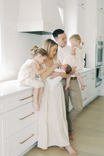 family standing in their kitchen looking at newborn baby