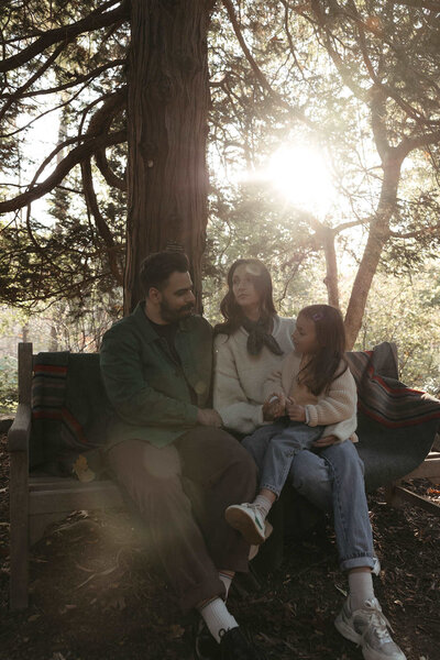 Family of 3 photography session sitting on a bench under a tree