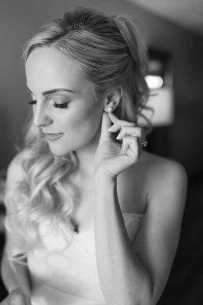 Beautiful bride in black and white  putting her earrings on