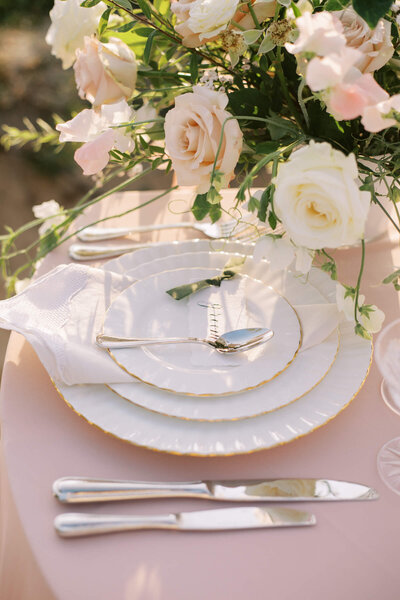 Een stijlvolle tafelsetting met delicate bloemen, glanzend bestek en porseleinen borden, perfect voor een romantische bruiloft.