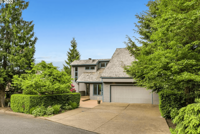 The front of a house with a large garage and large tree to the side.