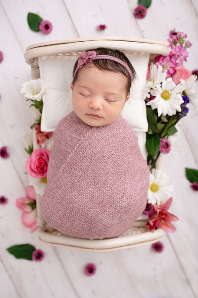 Newborn baby wrapped in pink sleeping with a pink headband