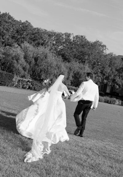 Bride and groom running through a field holding hands by east coast photographers