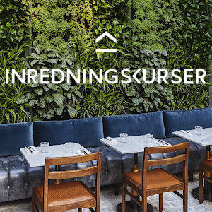 Restaurant with green wall, blue banquette with leather button tufted seats and velvet back cushions. Dining tables with marble tops and metal base. Wooden dining chairs with leather seats