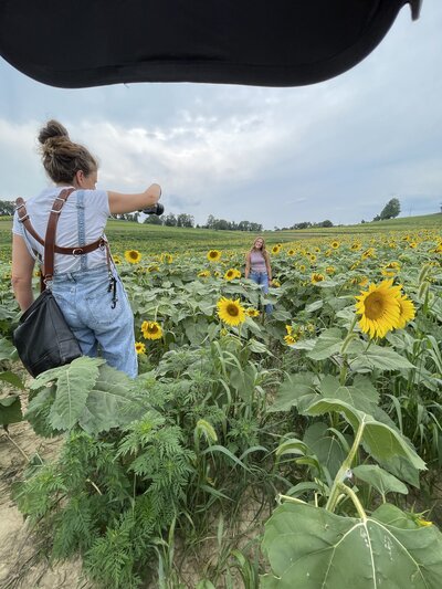 An image of heidi iliff holding a camera as she takes photographs of a senior during a session.