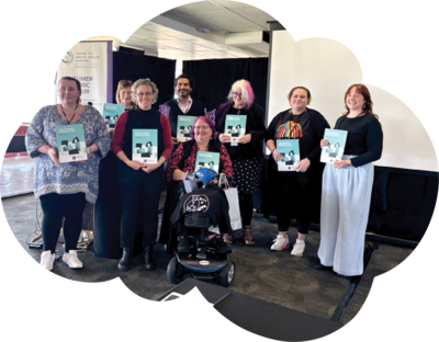 A group of 2024 attendees, all gathered around with a flyer in their hands.