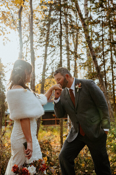 groom kisses brides hand at their Fall Alaska wedding