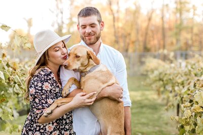 Engaged couple hold their dog in a field for Minneapolis engagement photography session.