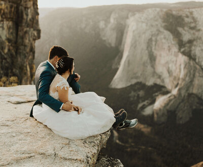 bride & groom sitting on cliff