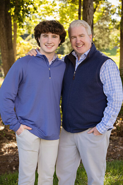 Elegant autumn portrait of parents standing together near brick terrace steps at UNCC Botanical Garden Charlotte NC, smiling confidently at the camera