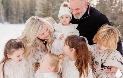 A happy mom chats with her four young daughters in a snowy mountain