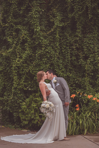 Couple kissing in front of greenary at a beautiful Barn Wedding in Michigan