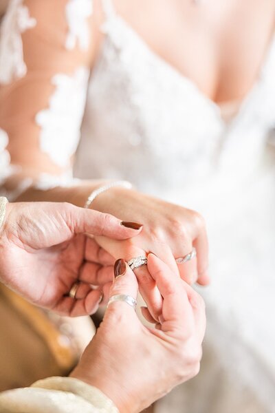 Champagne bottle & glasses styled with blooms, petals, ribbon, and wedding rings in a ring box.