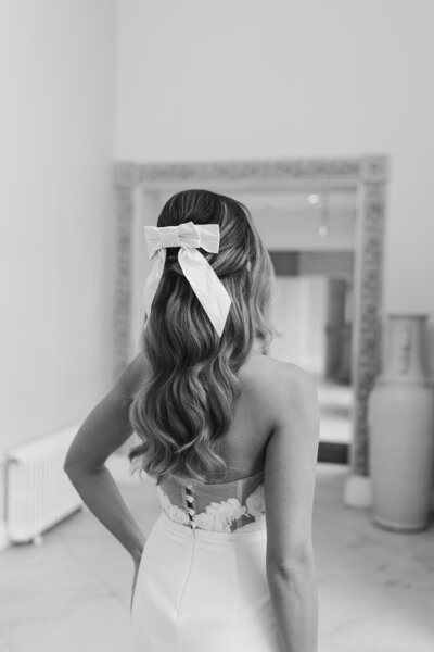 Modern sleek half up half down hairstyle with a wave and Victoria Fergusson bow accessory, Ashridge House Wedding