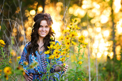 High school senior picture with girl in sunflowers at sunset